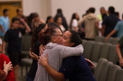 Two women hugging in a auditorium