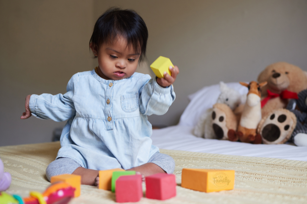 a baby with down syndrome playing with toy blocks